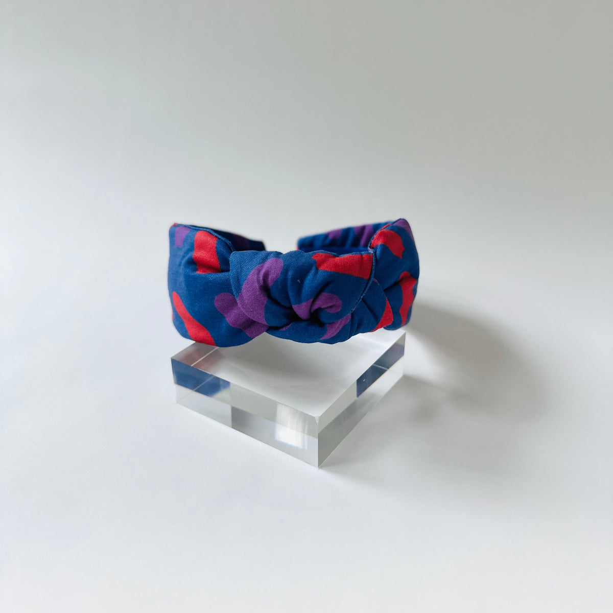 Colorful headband on a clear stand against a white background