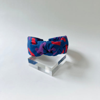 Colorful headband on a clear stand against a white background