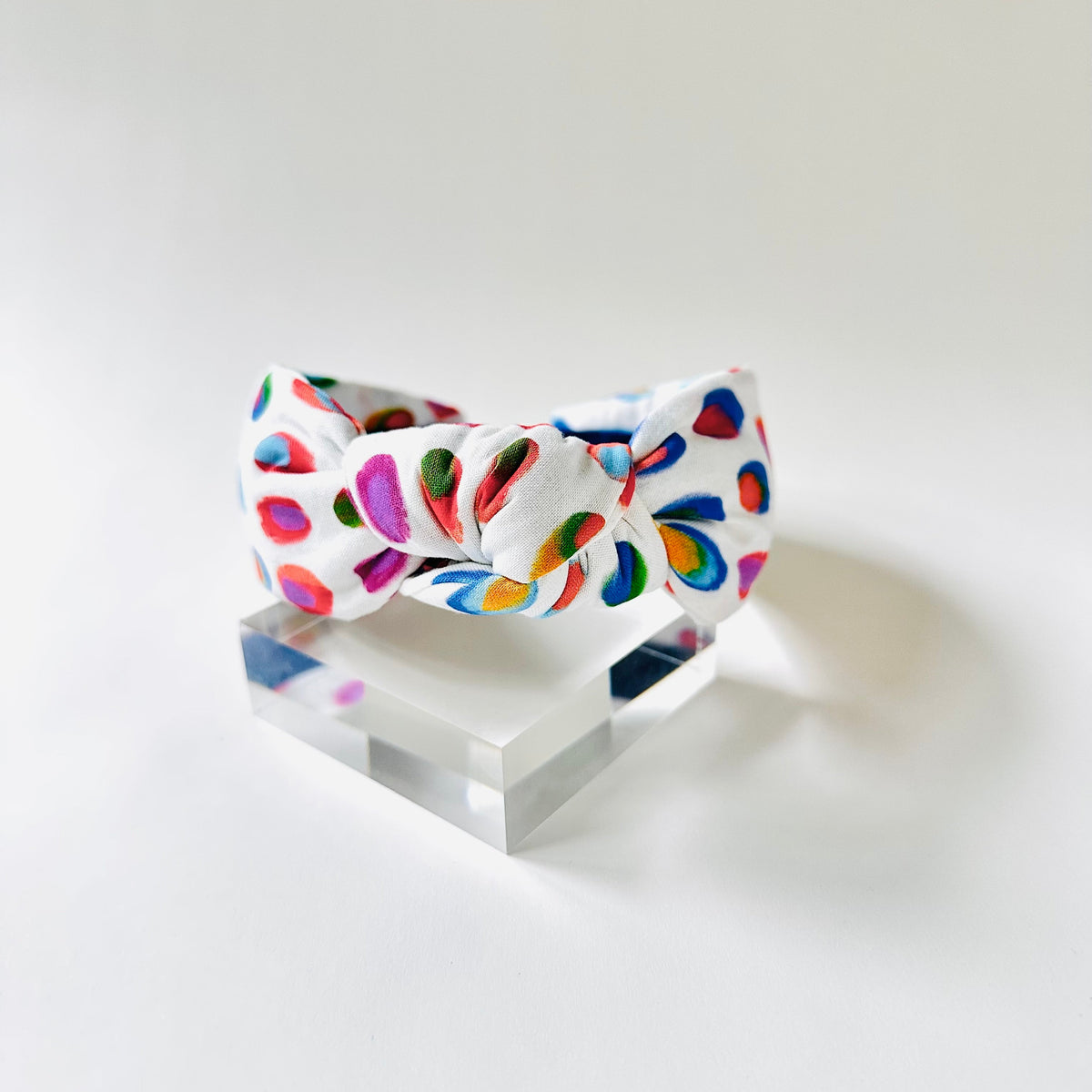 Colorful bow-shaped object on a clear stand against a white background