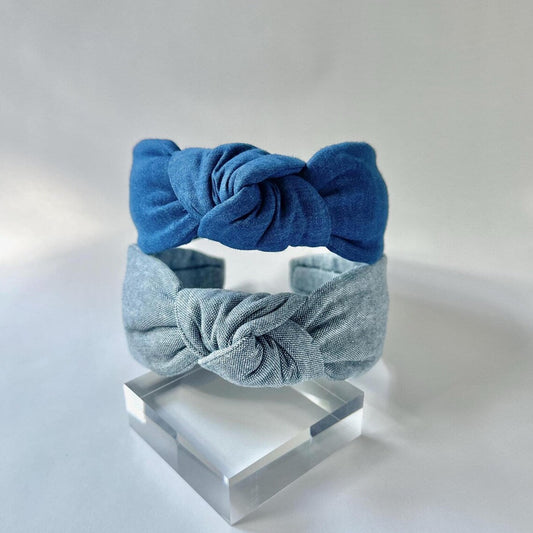 Two blue headbands on a clear stand against a light gray background